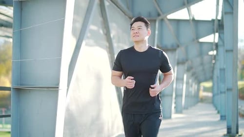 young asian runner running on modern urban stadium background. Morning jog sports Athletic man