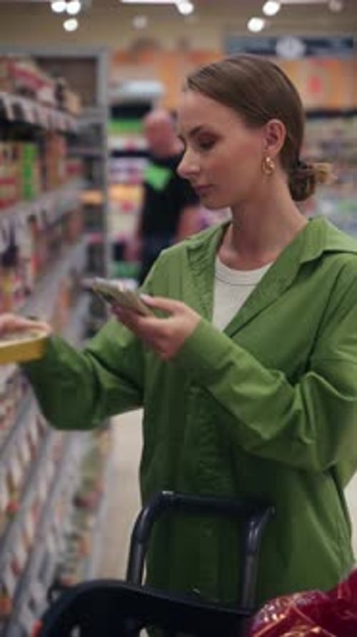 Woman Using Smartphone Scanning Product in Supermarket