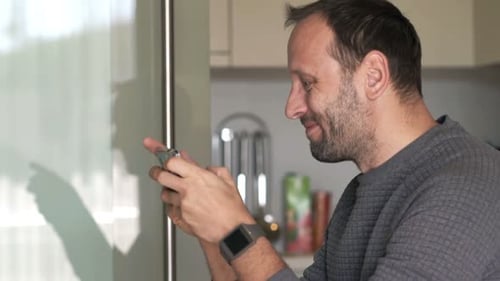 Man Smiling While Looking at His Mobile Phone