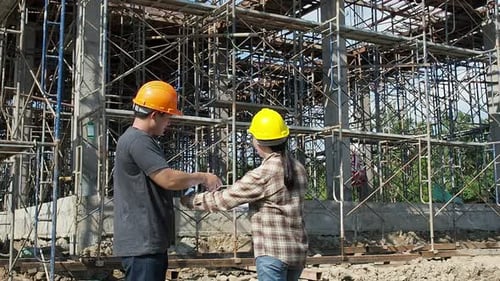 Construction manager and engineer discussing and checking plans on construction site.