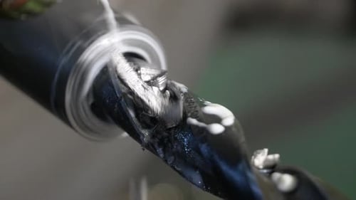 Drilling detail on lathe with metal shavings.