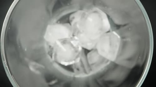 Ice cubes falling into a glass, Top view on a black background, slow motion, macro