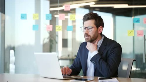 Focused Man Working on Laptop in Modern Office