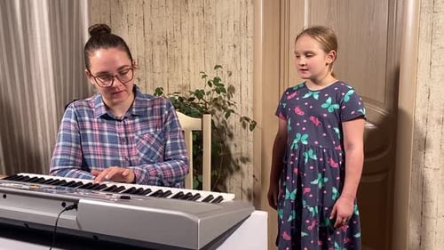Woman Plays Keyboard as Girl Sings Along