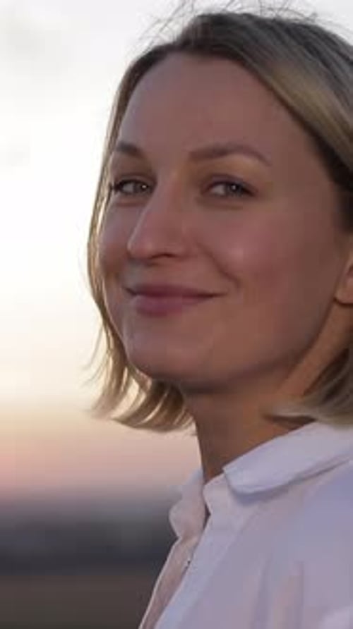 Une femme sereine aux beaux cheveux blonds fluides capturée gracieusement devant un magnifique coucher de soleil