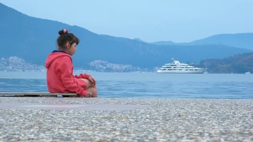 Young Child Sitting on Pier by the Ocean