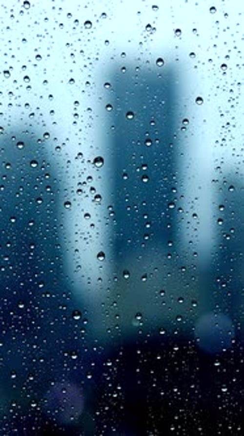Rain Drops on Window with Blurred City Background