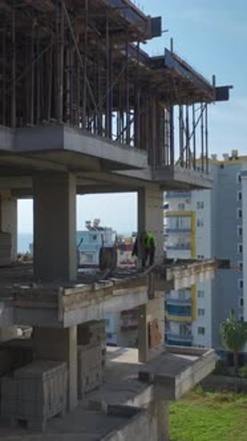 Vertical Video Aerial View of Construction Teams Building Structural Walls Using Concrete and Metal