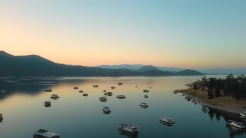 Aerial drone flying over a lake, water dam, with mountains at sunrise. Beautifull dreamy landscape
