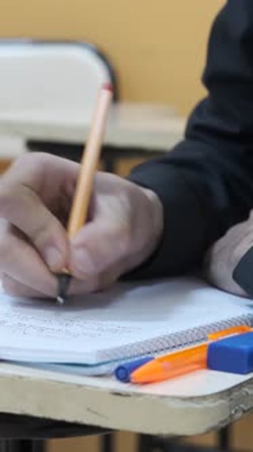 Hand Writing in Notebook at School Desk