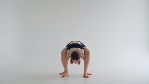 Fille en équilibre dans la pose de luciole pendant la pratique du Hatha Yoga