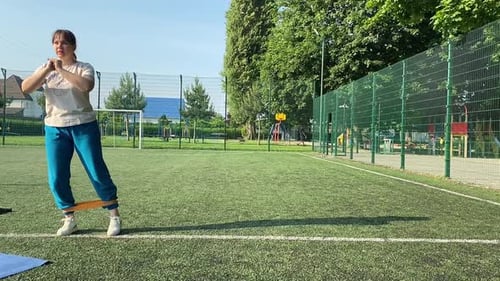 Jovem mulher se aquece na área esportiva ao ar livre