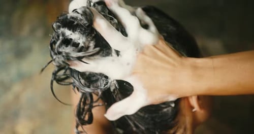Woman Massaging Shampoo into Wavy Dark Hair