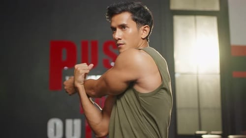 Asian handsome sportsman stretching body before exercise in gym club.