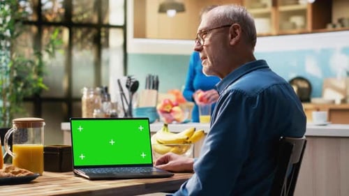 Chroma Key Laptop with Retired Man Checking Display at the Table in Rustic Kitchen