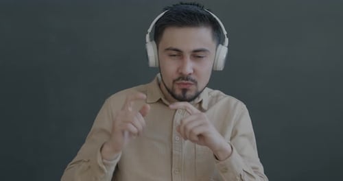 Young Man Dances with Headphones on Gray Background