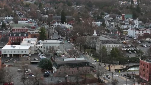 Vehicles on main street in small american town during cloudy day in winter. Aerial approaching wide