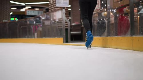 CloseUp of Skater in Blue Skates and Black Trousers on Ice Rink