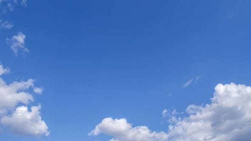 De légers nuages blancs volent sur un ciel bleu éclatant
