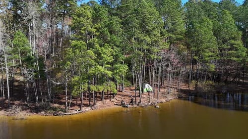 Family Resting in Nature Tent Near a Quiet Lake Surrounded By Lush Trees and Dense Forest
