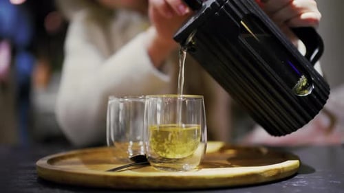 Close up of tea being poured from a French press into transparent glass cups