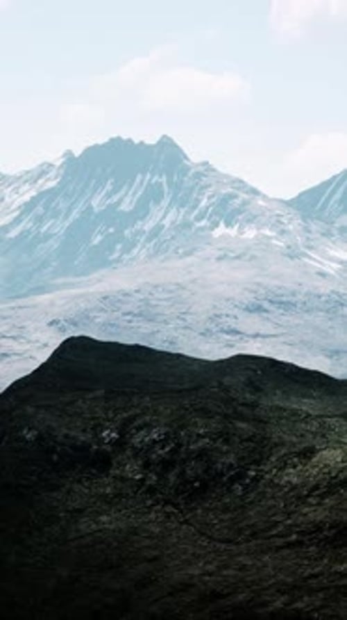 Aerial Over Valley With Snow Capped Mountains In Distance