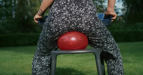 Adult Sits on Children's Toy with Red Balloon