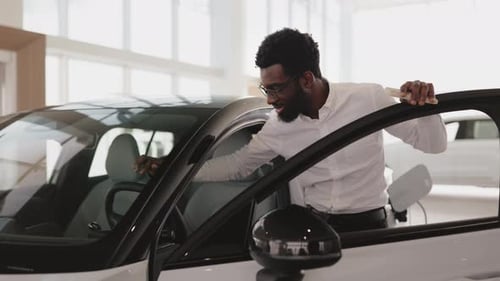 Young African Male Choosing Auto Wants to Buy New Automobile in Car Showroom