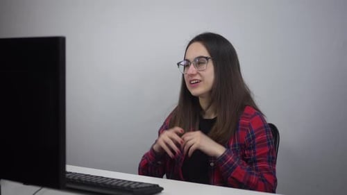 A Young Woman is Talking on a Video Link While Sitting in the Office in Front of a Pc