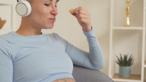 Pregnant Woman Eating Sweets during Movie Watching at Home