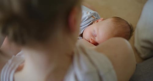 Mother Holds Sleeping Newborn Baby Indoors