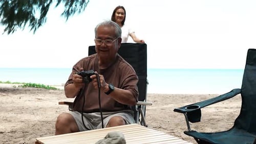 Happy Senior Man and Young Adult at Beach with Camera