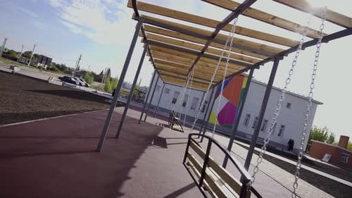 Children Playground with Swinging Benches on Territory of School