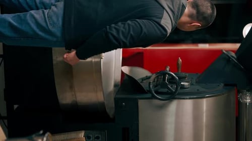 Vertical Video Coffee Roasting Factory Worker Stands Near the Roasting Machine and Monitors the