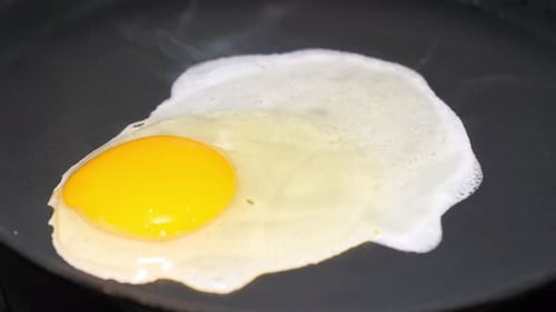 The Slow Motion of the Egg Falls Into the Pan and is Fried on the Gas Stove