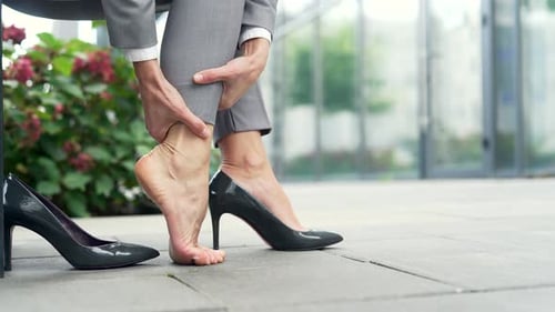 Close up. Female hands massaging leg calf muscle cramps. Businesswoman suffers from leg pain, calf