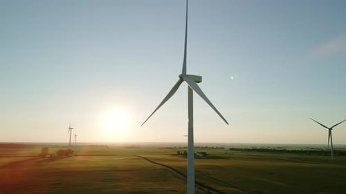 Wide Aerial Drone View of a Wind Farm Park with Wind Turbines Standing in a Wheat Field at Sunset