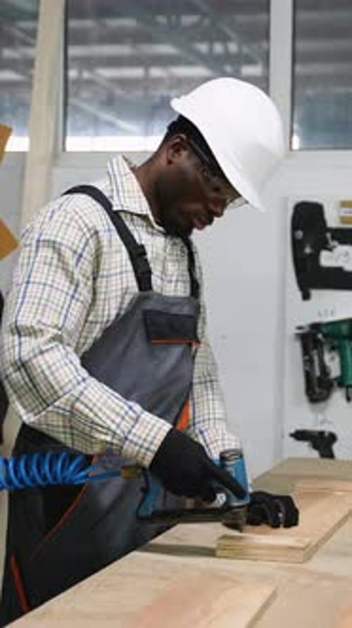 Carpenter Using Staple Gun to Join Wooden Boards