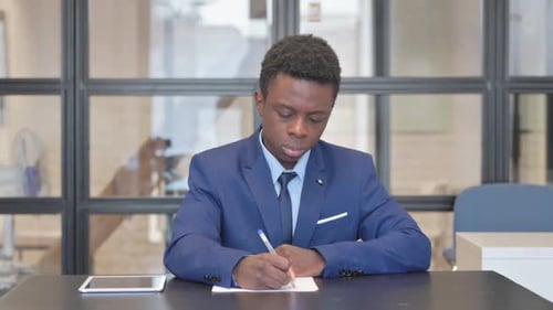 African Businessman Writing a Letter in Office