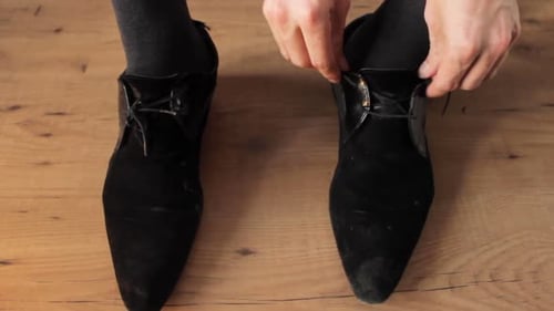 Close up shot of business man tying up his black shoe lace.