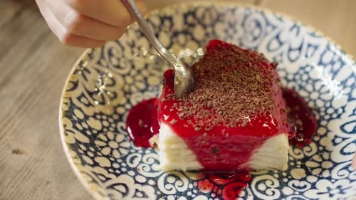 Spoon Taking Bite of Dessert with Red Topping