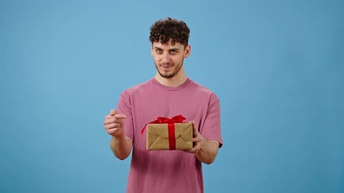 Charming Caucasian Man Holding Out at Camera a Cute Gift Box for St Valentines Women's Mother's Day