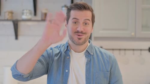 Man Waving Hello in an Indoor Setting