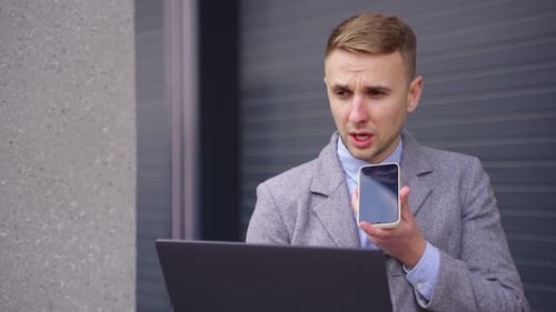 Young Adult Man Speaking on Phone with Laptop