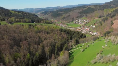 Aerial view of a small village in a valley surrounded by hills and forest of the blackforest, German