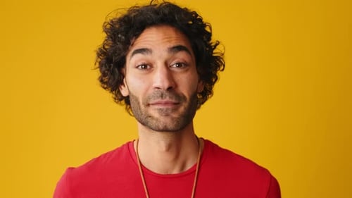 Close up, surprised man covers his mouth with palms looking at camera isolated on yellow background