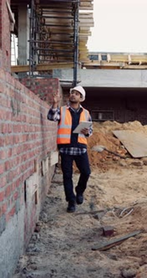 Construction, man and brick wall inspection with tablet for masonry, progress report or safety code