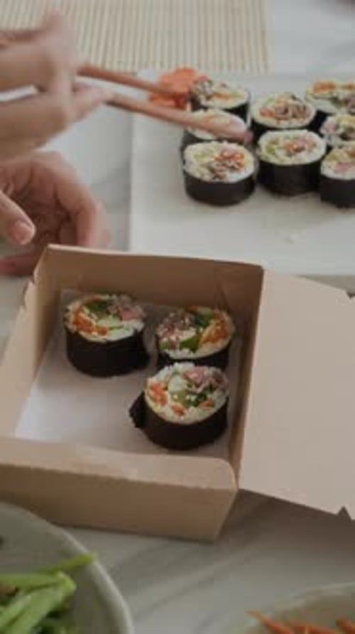 Anonymous Woman Using Chopsticks while Putting Self-made Kimbap in Carton Box