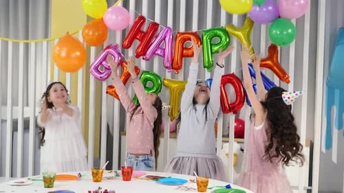 Girls Celebrate Birthday Party with Balloons and Cake