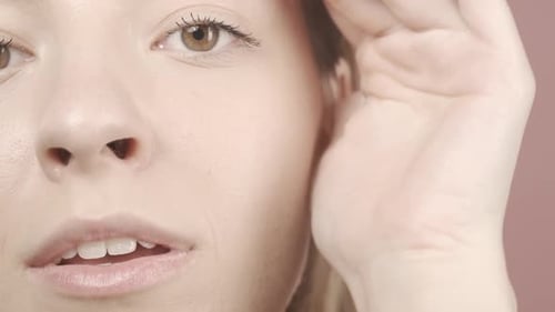Cropped Shot of a Woman's Face in the Studio on a Pink Background Close Up A Woman Runs Her Hand
